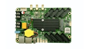 Prototype development board featuring a large CPU heatsink, many edge connectors, a yellow coin-cell battery, and USB ports.