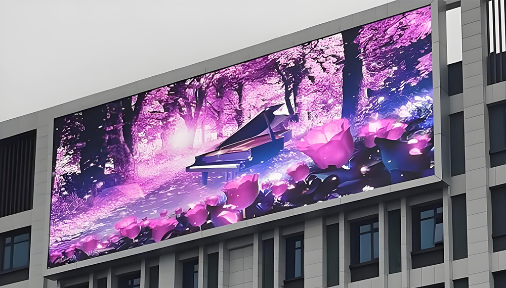 Large outdoor billboard on a modern building showing a grand piano amid pink flowers in a purple forest scene.