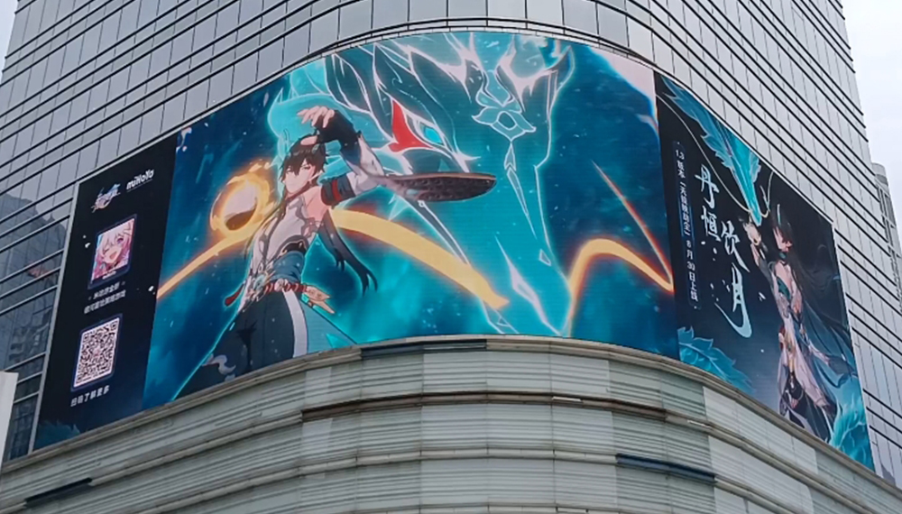 Large curved billboard on a glass-fronted building displaying anime artwork: a warrior in white/blue with a glowing yellow arc and teal energy background.”]}{